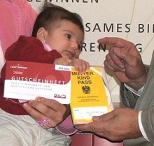 Baby mit Impfgutscheinheft und Mutter-Kind-Pass.