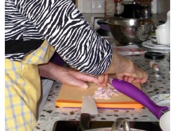 Hilfsmittel wie der Zwiebelschneider für Einhänder und rutschfeste Folien unter dem Schneidebrett erleichtern Frau P. nach dem Schlaganfall den Alltag.